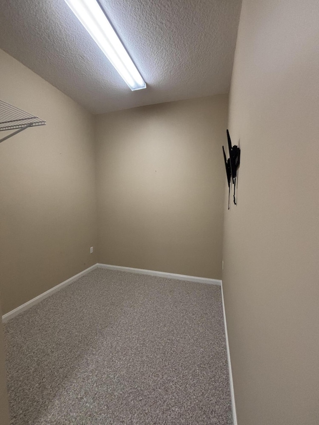 carpeted spare room featuring baseboards and a textured ceiling