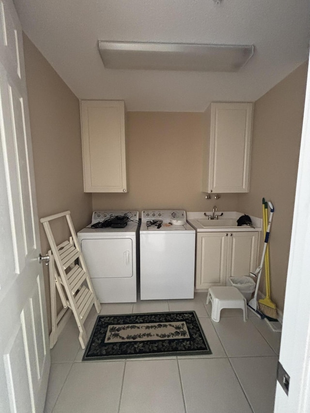 washroom with a sink, cabinet space, washer and clothes dryer, and tile patterned flooring