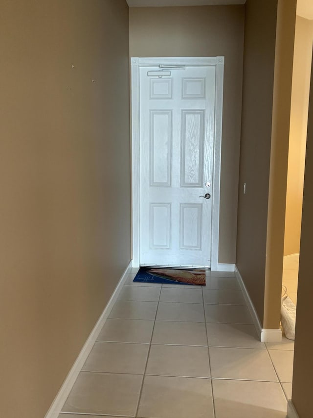 doorway featuring light tile patterned floors and baseboards