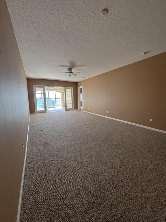 empty room with baseboards, a ceiling fan, carpet flooring, and a textured ceiling