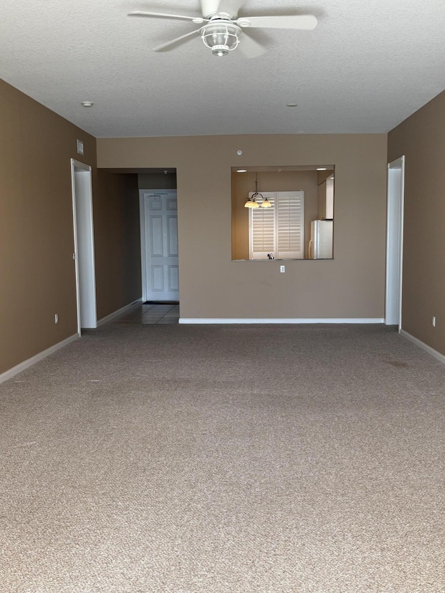 empty room with baseboards, a textured ceiling, carpet floors, and ceiling fan