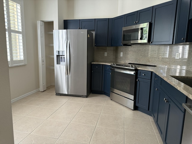 kitchen featuring light tile patterned flooring, appliances with stainless steel finishes, tasteful backsplash, and light stone counters