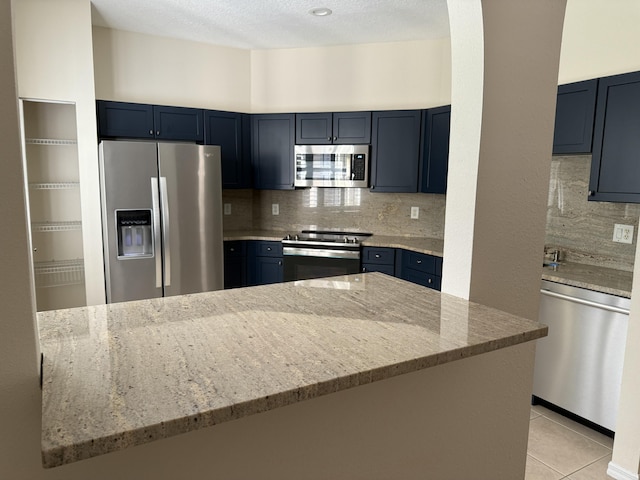 560 SW Indian Key Dr S, Saint Lucie West, FL 34986 - kitchen with appliances with stainless steel finishes, light tile patterned flooring, light stone countertops, and backsplash