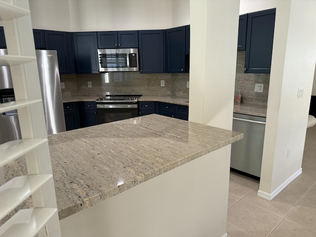 560 SW Indian Key Dr S, Saint Lucie West, FL 34986 - kitchen with light tile patterned floors, blue cabinetry, light stone counters, backsplash, and appliances with stainless steel finishes
