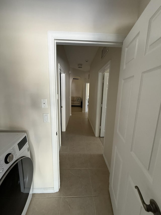 clothes washing area with visible vents, washer / clothes dryer, light tile patterned floors, baseboards, and laundry area