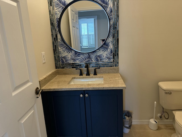 half bathroom featuring tile patterned flooring, toilet, vanity, and baseboards