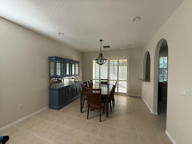 dining area with light tile patterned floors, visible vents, a textured ceiling, and baseboards