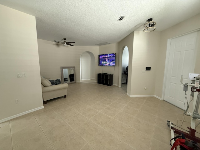 living room with arched walkways, a textured ceiling, and a ceiling fan