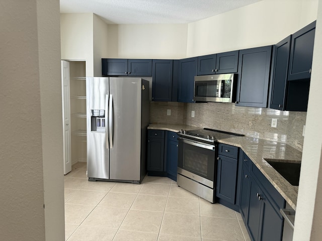560 SW Indian Key Dr S, Saint Lucie West, FL 34986 - kitchen with light stone countertops, a sink, light tile patterned flooring, tasteful backsplash, and appliances with stainless steel finishes