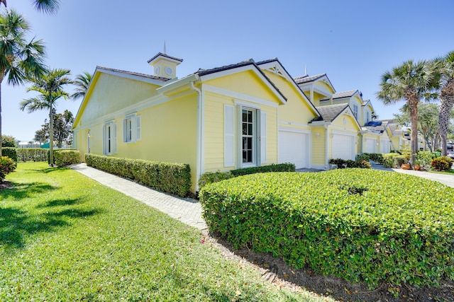 view of property exterior with a garage, a lawn, and stucco siding