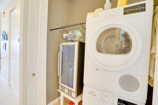 laundry area with stacked washer and dryer, wine cooler, light tile patterned floors, baseboards, and laundry area