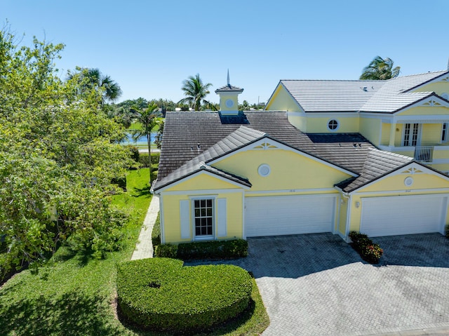 view of front of property with a garage, decorative driveway, stucco siding, and a tiled roof