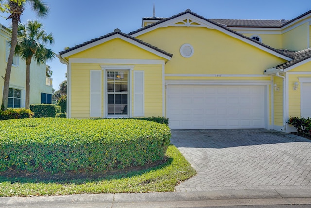 view of front of house with decorative driveway, an attached garage, and stucco siding