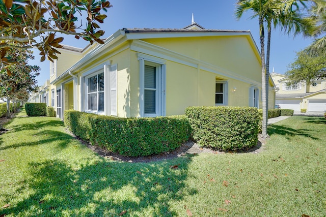 view of side of property with stucco siding and a yard