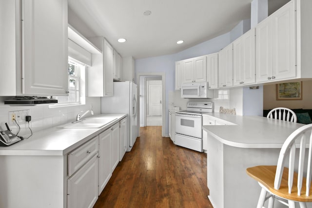 2853 White Trout Ln, West Palm Beach, FL 33411 - kitchen with white appliances, a sink, a peninsula, a kitchen bar, and white cabinets