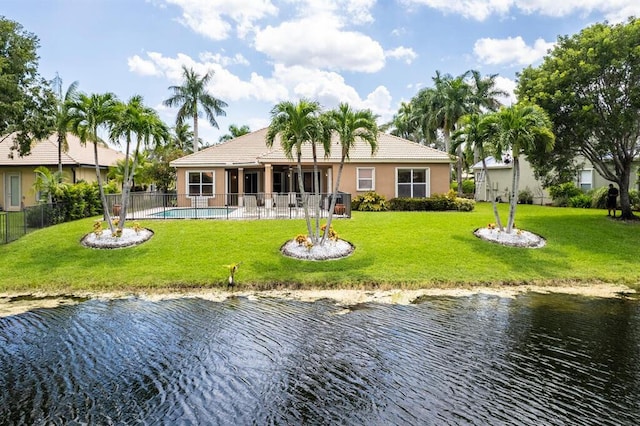 back of house with a fenced in pool, fence, stucco siding, a water view, and a lawn