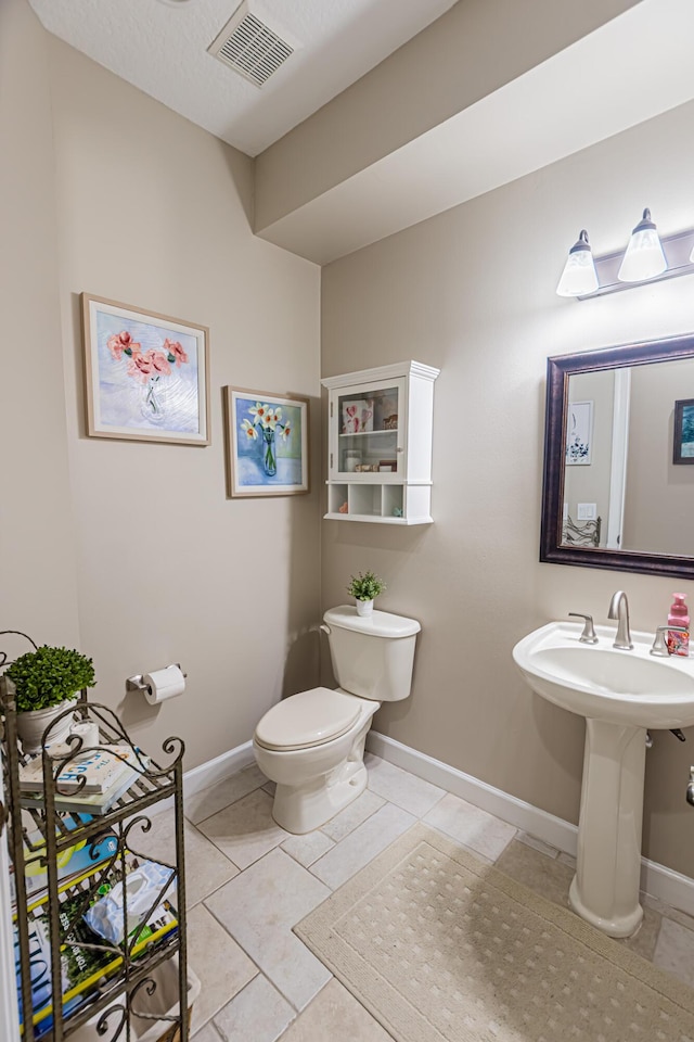 half bath with tile patterned flooring, visible vents, toilet, and baseboards