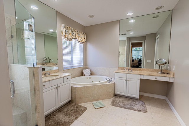 bathroom featuring tile patterned floors, a jetted tub, a stall shower, and a sink