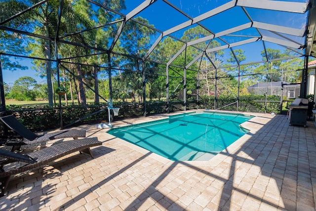 pool featuring glass enclosure, a patio, and grilling area