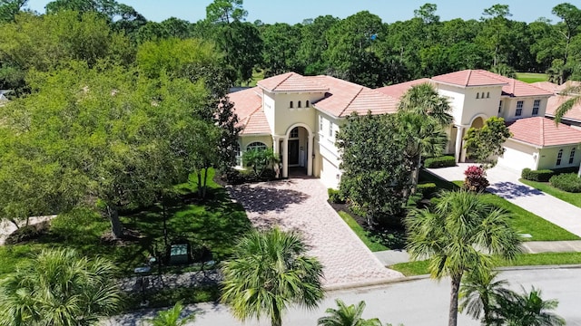 mediterranean / spanish home featuring decorative driveway, an attached garage, stucco siding, and a tiled roof