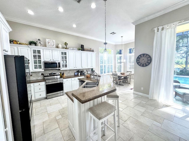 kitchen featuring a sink, decorative backsplash, appliances with stainless steel finishes, a kitchen bar, and crown molding