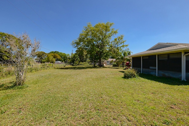 view of yard featuring fence and a sunroom