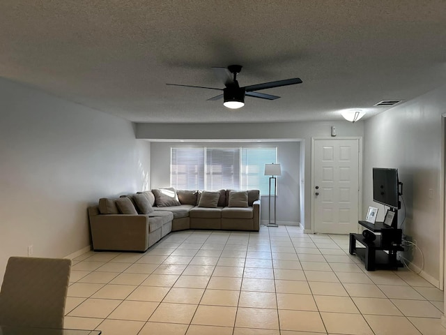 unfurnished living room with light tile patterned floors, a ceiling fan, baseboards, visible vents, and a textured ceiling