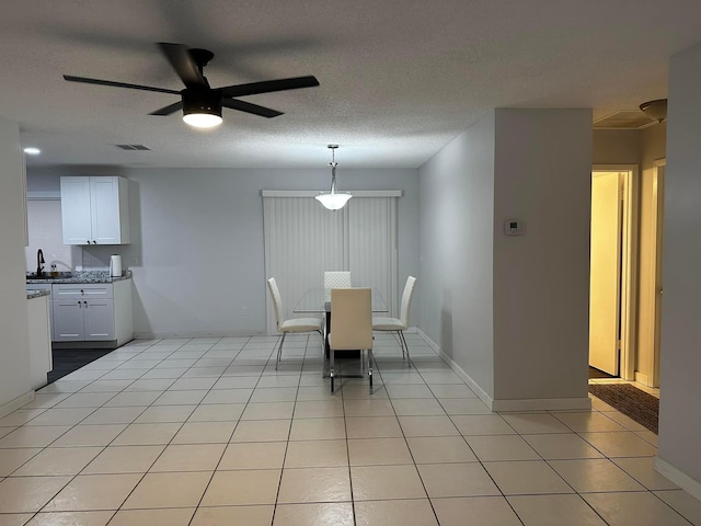 unfurnished dining area featuring light tile patterned floors, baseboards, visible vents, and a textured ceiling