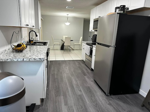 kitchen featuring dark wood-style floors, visible vents, a sink, white cabinets, and appliances with stainless steel finishes