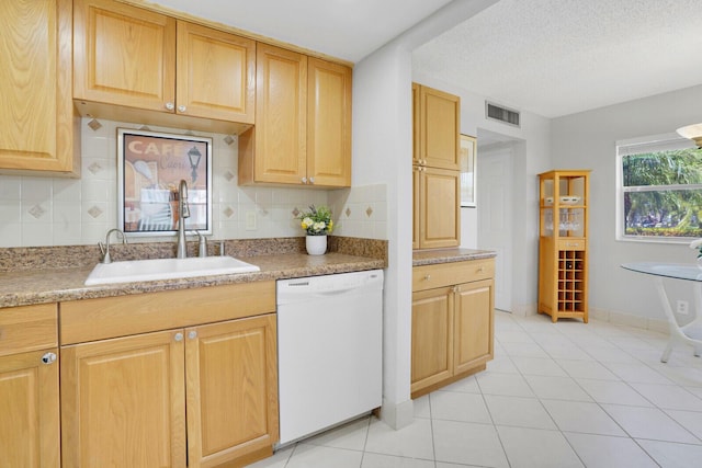 kitchen featuring a sink, visible vents, tasteful backsplash, and white dishwasher