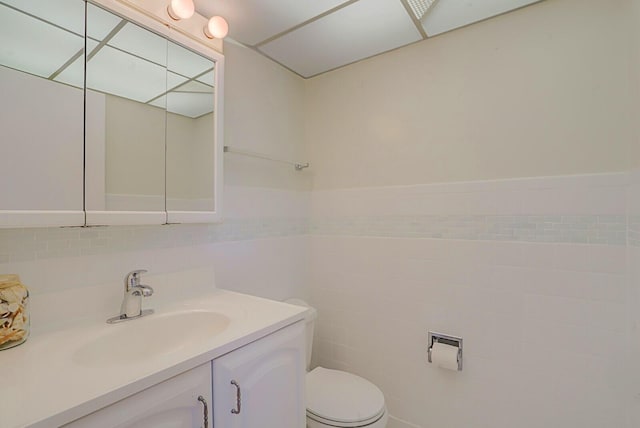 bathroom with vanity, toilet, and tile walls