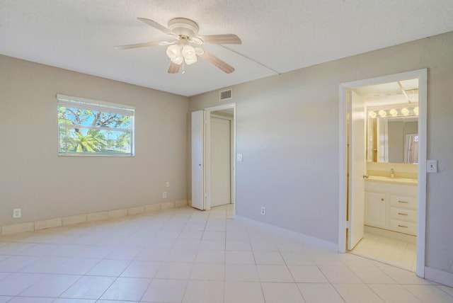 unfurnished bedroom with light tile patterned flooring, baseboards, visible vents, and ensuite bathroom