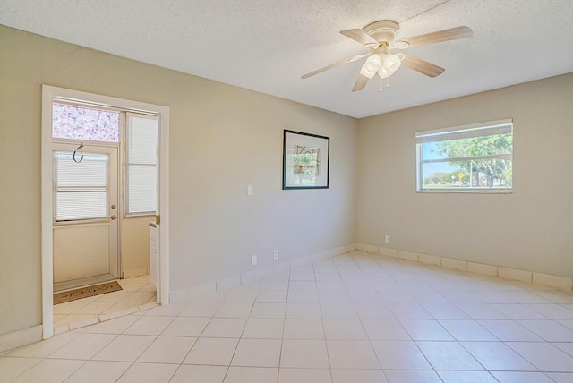 spare room with baseboards, a textured ceiling, ceiling fan, and light tile patterned flooring