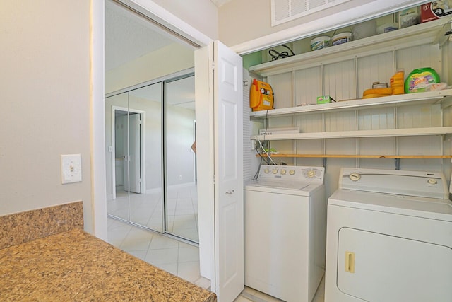 clothes washing area with laundry area, light tile patterned floors, and washing machine and dryer