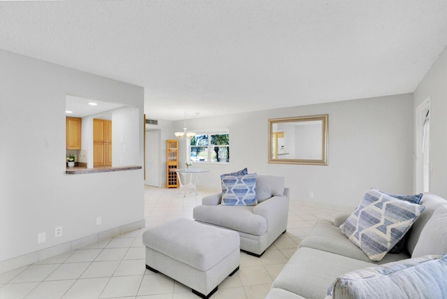 living room with light tile patterned floors, baseboards, a textured ceiling, and an inviting chandelier