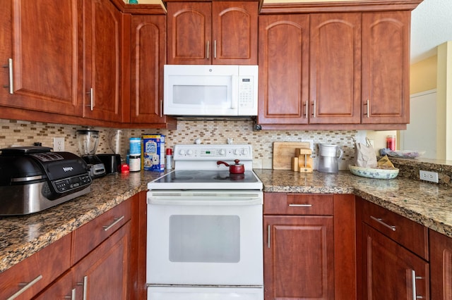 kitchen with backsplash, white appliances, and dark stone countertops