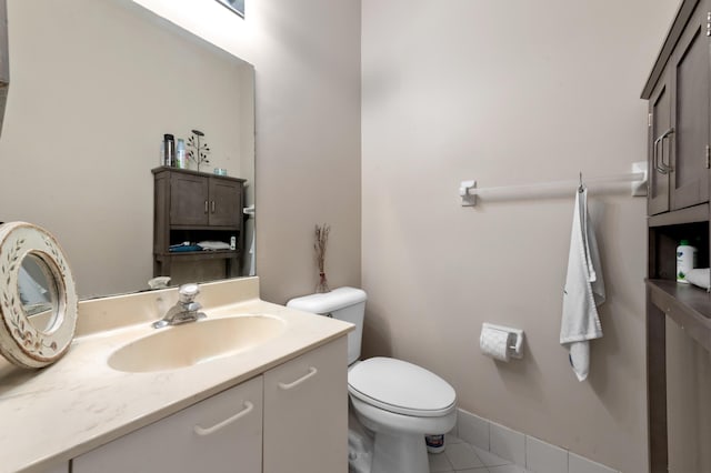 half bathroom featuring tile patterned floors, baseboards, toilet, and vanity