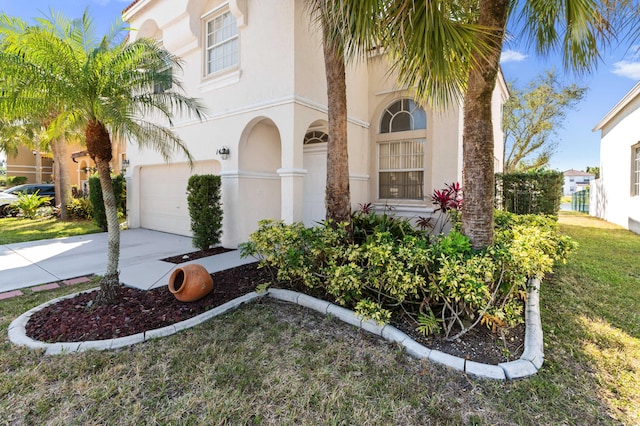 view of front facade with stucco siding, a front lawn, concrete driveway, and a garage