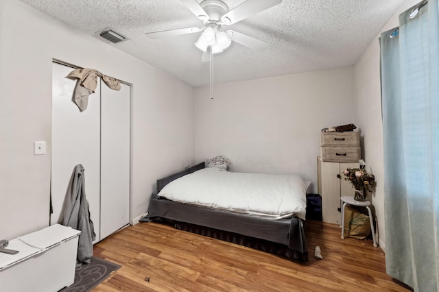 bedroom featuring visible vents, a textured ceiling, ceiling fan, and wood finished floors