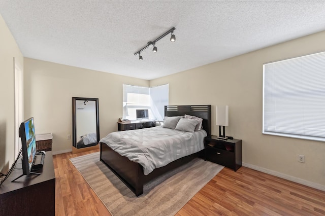 bedroom featuring a textured ceiling, baseboards, and wood finished floors