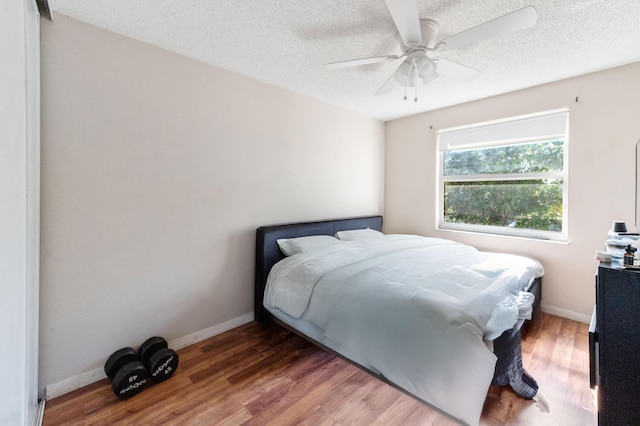 bedroom with baseboards, a textured ceiling, wood finished floors, and a ceiling fan