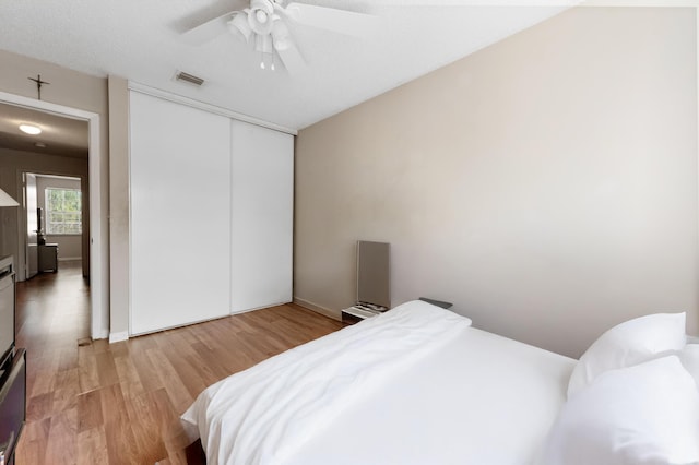 bedroom with visible vents, ceiling fan, baseboards, light wood-style floors, and a closet