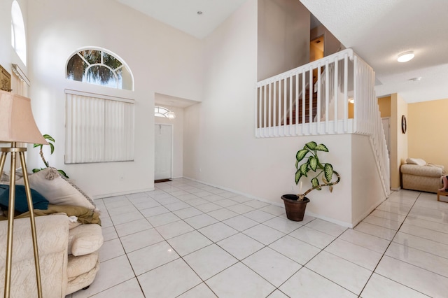 tiled entryway with stairway, baseboards, and a towering ceiling