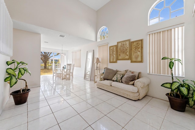 living area with a high ceiling, light tile patterned floors, and visible vents