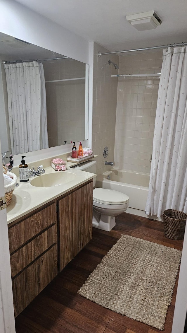 bathroom with toilet, wood finished floors, vanity, and shower / bath combo with shower curtain