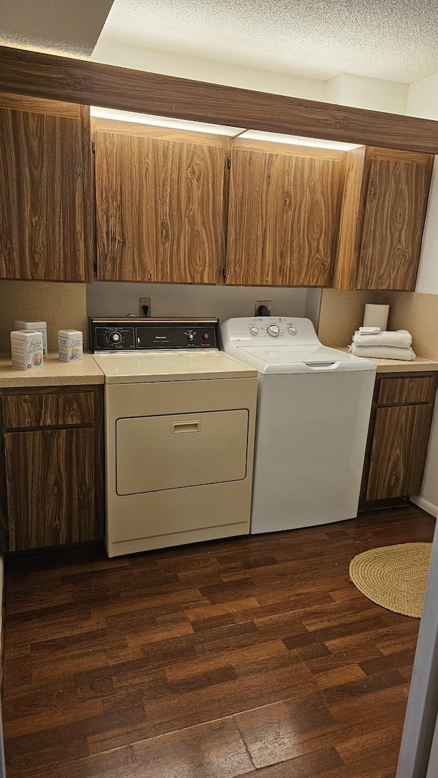 laundry area featuring separate washer and dryer, cabinet space, dark wood-type flooring, and a textured ceiling