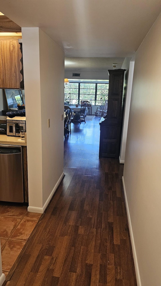 hall featuring baseboards, dark wood-style floors, and visible vents