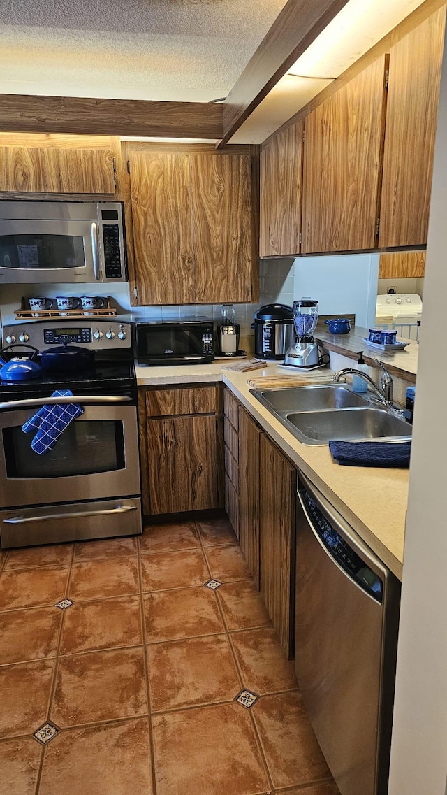 kitchen featuring light countertops, tile patterned flooring, a sink, and stainless steel appliances