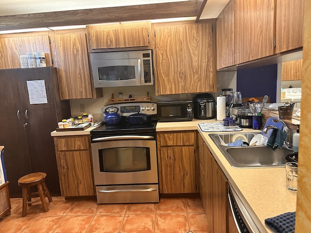 kitchen featuring a sink, stainless steel appliances, light tile patterned flooring, and light countertops