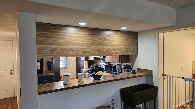 kitchen featuring black microwave, recessed lighting, wood counters, and stainless steel fridge